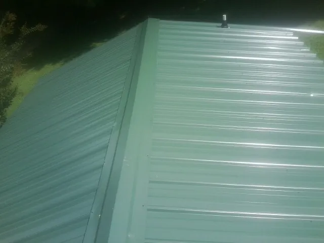 New green metal panels meeting at the ridge of a roof — Flat Roof Repair work by our crew in West Hartland