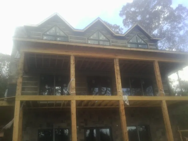 Dormers and porch framing on a large log home under construction — Roof Coating work by our crew in West Hartland