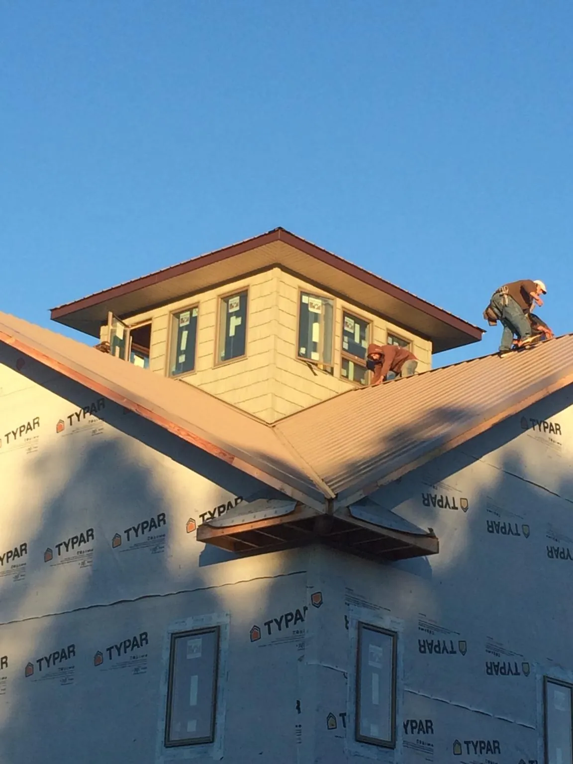 Roofers working around a rooftop cupola on a new metal roof at sunset — Roof Waterproofing in West Hartland by Roofing Brothers